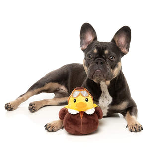 Franse Bulldog ligt met FuzzYard Waddle Squad-dle Amelia Quackhart – pluche hondenspeeltje in de vorm van een gele eend verkleed als piloot, met vintage bruine vliegjas, witte bontkraag en pilotenbril, knuffelspeelgoed voor honden