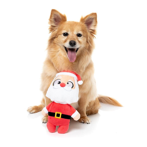 Hond zit achter een pluche kerstman als hondenspeeltje met rode muts en witte baard