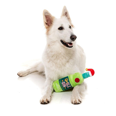 FuzzYard Xmas Gin-gle Gin – hond ligt met pluche hondenspeeltje in de vorm van een fles gin met kerstmuts
