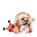Hond ligt met een pluche kerstman als hondenspeeltje tussen de voorpoten