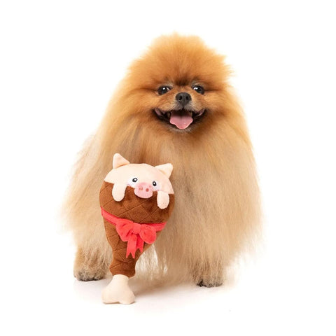 Hond samen met FuzzYard Ham a Merry Pigmas – feestelijk hondenspeelgoed met biggenkop en rode strik